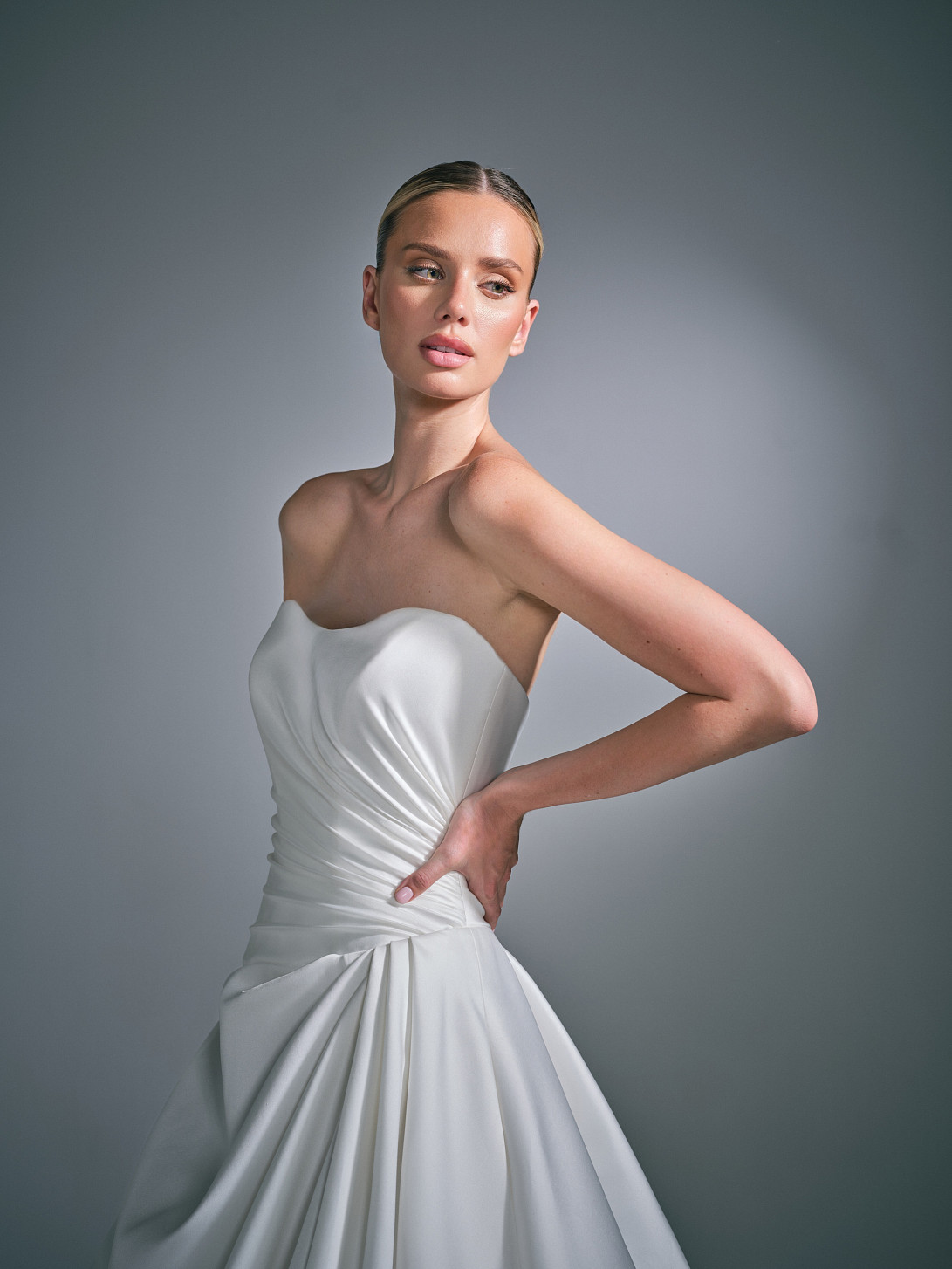 Cassielle by Suzanne Neville, a sculptural Mikado ballgown wedding dress with hand draping, a rounded scoop neckline and asymmetric dropped waist.