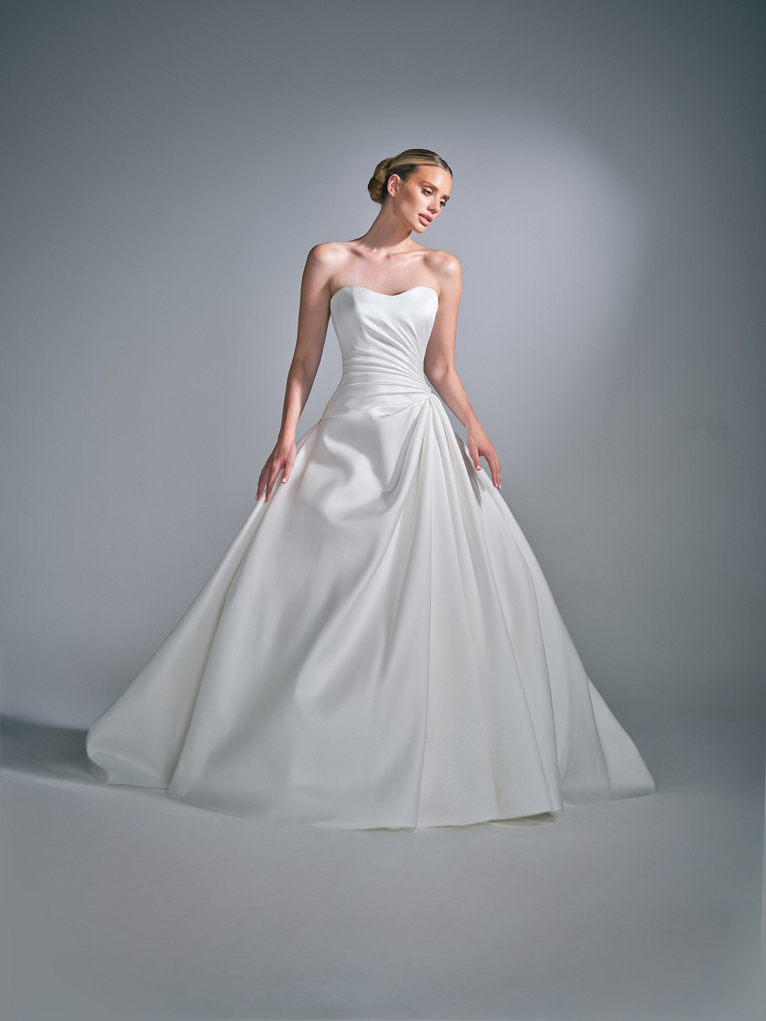 Side profile of the Cassielle ballgown wedding dress, highlighting the asymmetric dropped waist and volume of the skirt