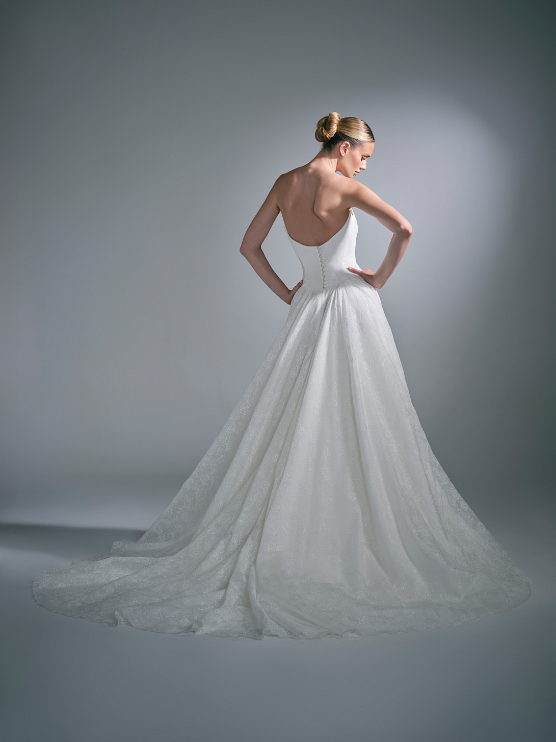 Back view of the Clovelle wedding gown, showing covered button detailing and a flowing skirt train.