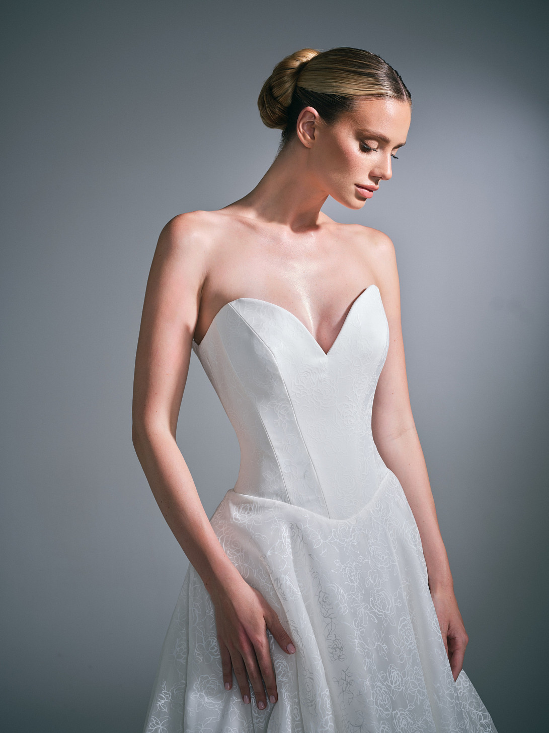 Front view of the Clovelle wedding dress by Suzanne Neville from the ICON 35 collection, displaying a sculpted silhouette and hand printed floral organza