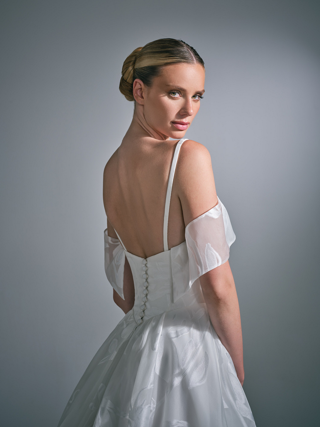 Side profile view of the Suzanne Neville Liora wedding gown, displaying the contoured waistline and elegant fabric drape.