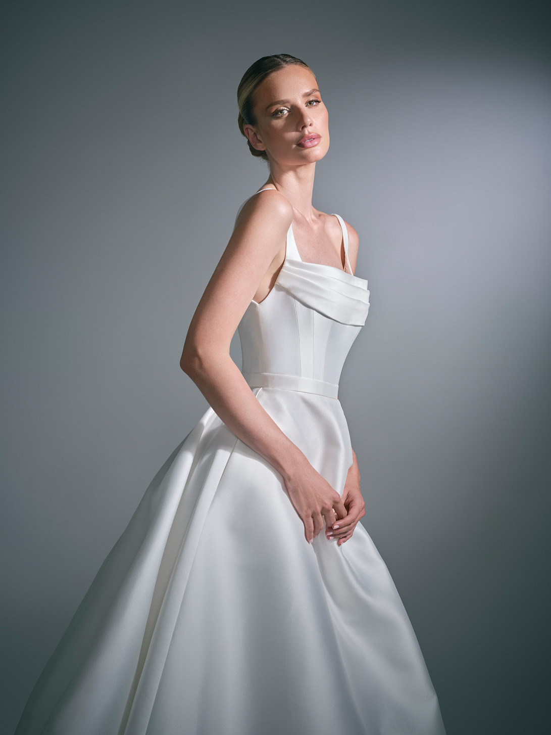 Lysenne has structured bodice that features a modern square neckline, slender straps and a gently draped panel across the bust, bringing softness and femininity to the clean architectural silhouette.